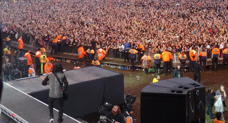 Security staff behind a Mojo Barrier line in front of a large festival crowd
